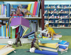 Toy dinosaurs in a miniature library landscape